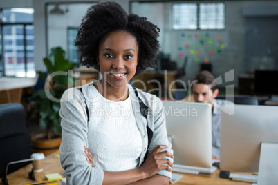 Happy woman with arms crossed standing in office