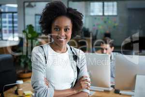 Happy woman with arms crossed standing in office