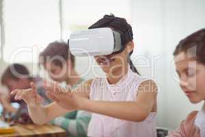 School girl sitting in classroom using virtual reality headset