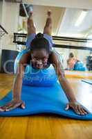 Portrait of fit woman performing pilate on exercise ball in fitness studio