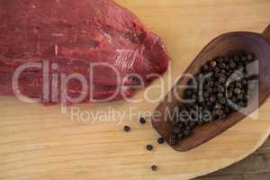 Beef steak and black pepper on wooden board
