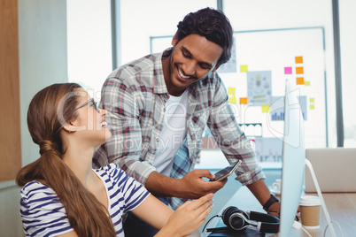 Male and female graphic designers interacting with each other at desk