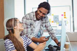 Male and female graphic designers interacting with each other at desk