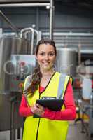 Female factory worker holding digital tablet