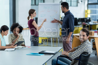 Portrait of smiling disabled business executive in wheelchair at meeting