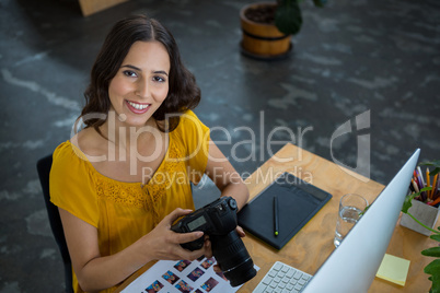 Smiling graphic designer holding digital camera in creative office