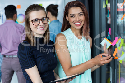 Portrait of business executives standing with sticky notes and marker