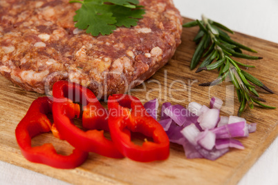 Beef patty and ingredients on wooden tray