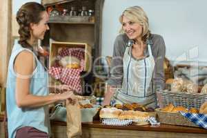 Smiling female customer interacting with bakery staff at counter