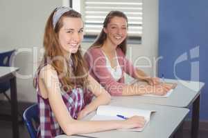 Portrait of happy schoolgirls sitting in classroom