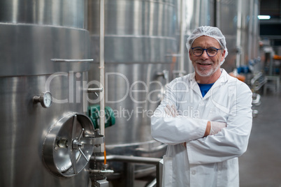 Smiling factory engineer standing with arms crossed in bottle factory