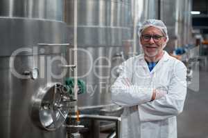 Smiling factory engineer standing with arms crossed in bottle factory