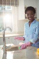 Portrait of woman cleaning utensils in kitchen sink
