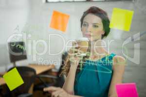 Thoughtful female executive looking at sticky notes