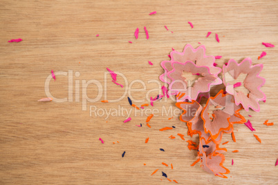 Colored pencils shavings on a wooden background