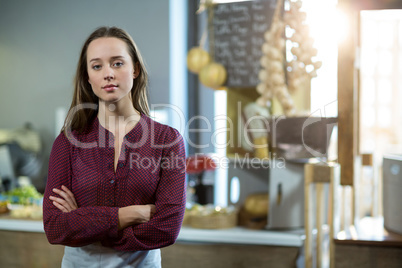 Portrait of smiling female staff standing with arms crossed against counter