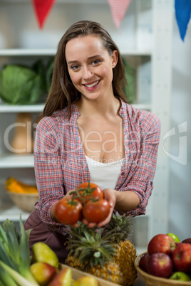 Smiling woman vendor offering tomatoes at counter