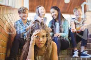 School friends bullying a sad girl in school corridor