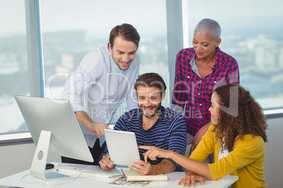 Graphic designers discussing over digital tablet