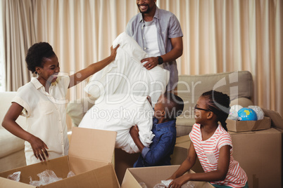 Parents and kids opening cardboard boxes in living room