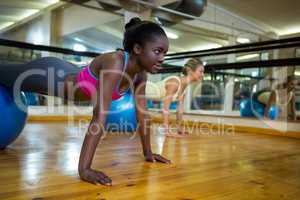 Woman doing pilates exercises on fitness ball with coach in fitness studio