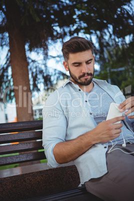 Executive sitting on park bench and using mobile phone