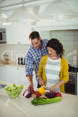 Smiling couple chopping vegetables in the kitchen