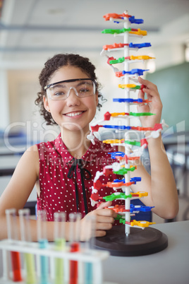 Portrait of happy schoolgirl experimenting molecule model in laboratory