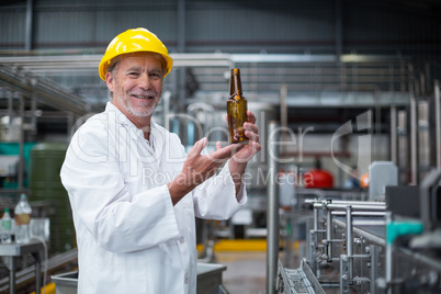 Factory worker examining a bottle in factory