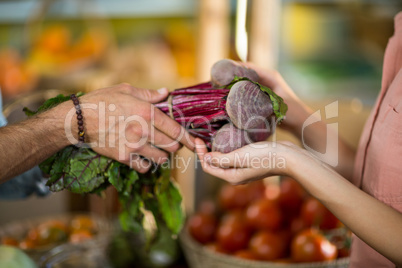 Vendor giving beetroot to the woman at the grocery store