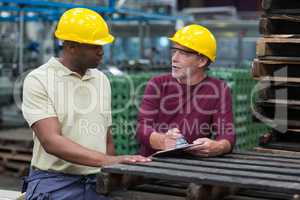 Factory workers discussing with a clipboard in drinks production plant