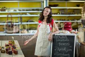 Female shop assistant standing besides menu chalk board