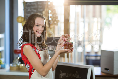 Female shop assistant holding a jar of jam