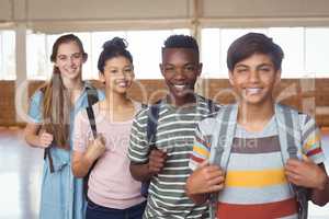 Portrait of happy students standing with schoolbags in campus