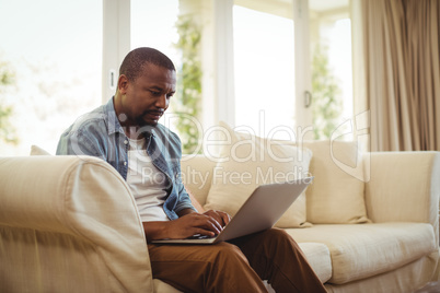 Man sitting on sofa and using laptop in living room