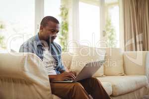 Man sitting on sofa and using laptop in living room