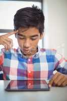 Schoolboy using digital tablet at desk