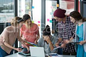 Colleagues with digital tablet and mobile phone talking to frustrated man