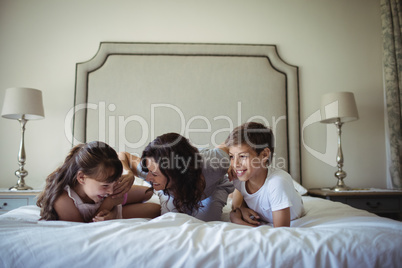 Mother and kids lying on bed in bedroom