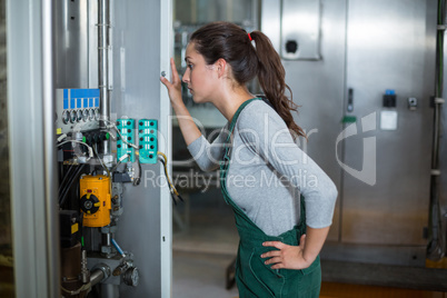 Female factory worker inspecting machinery