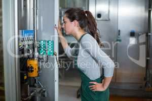 Female factory worker inspecting machinery