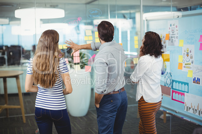 Team of business executives discussing over sticky notes in office