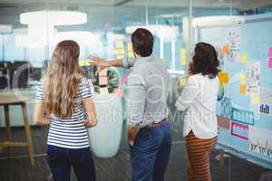 Team of business executives discussing over sticky notes in office