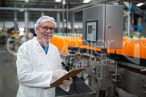 Smiling factory engineer maintaining record on clipboard in factory