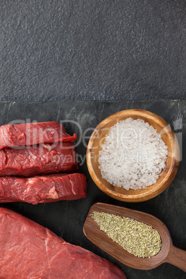 Beef steak, salt and spices on black slate plate