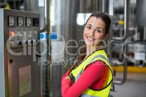 Portrait of female factory worker standing near machine