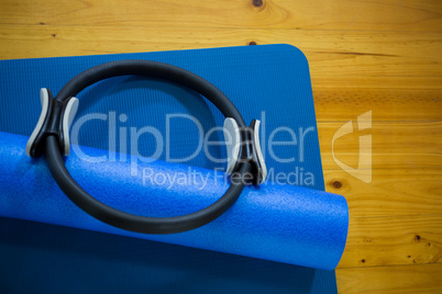 Pilates ring and exercise mat kept on wooden floor