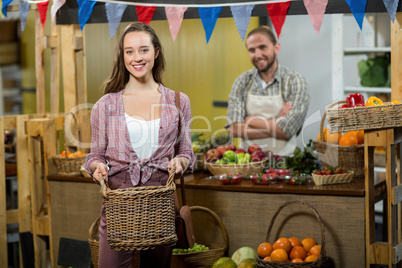 Smiling woman holding a basket at the counter in the grocery store