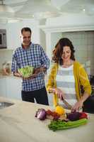 Smiling couple chopping vegetables in the kitchen