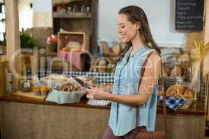 Smiling woman standing at counter using digital tablet